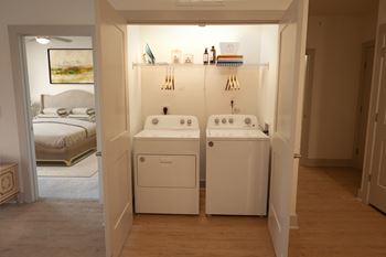 a laundry room with a washer and dryer and a bedroom with a bed